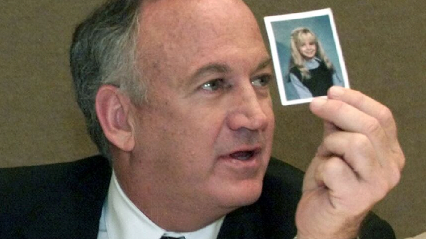 John Ramsey holding up a school photo of Jonbenet Ramsey